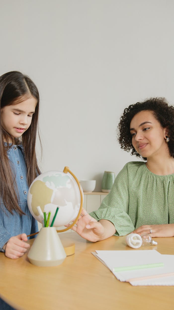 about-02 Young girl and woman exploring a globe together in an educational indoor setting.